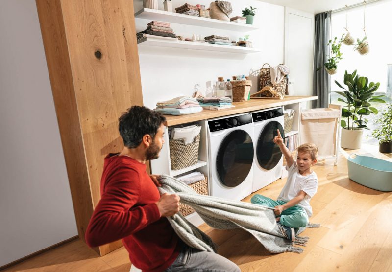 Син і батько граються перед пральною та сушильною машинами Gorenje.